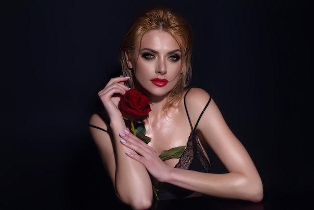 Amore e datazione sottile sexy bella donna con spalla nuda tenere rose rosse isolate sul retro dello studio