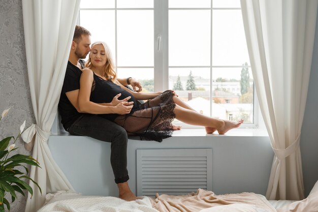 Amore e gravidanza. Il futuro padre tocca la pancia della moglie incinta. Le coppie alla moda abbracciano la pancia.