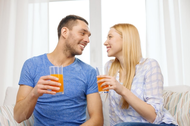 amore, famiglia, cibo sano e concetto di felicità - coppia felice sorridente che beve succo a casa