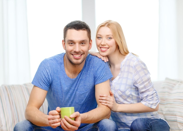 amore, famiglia, cibo sano e concetto di felicità - uomo sorridente con una tazza di tè o caffè con moglie o fidanzata a casa