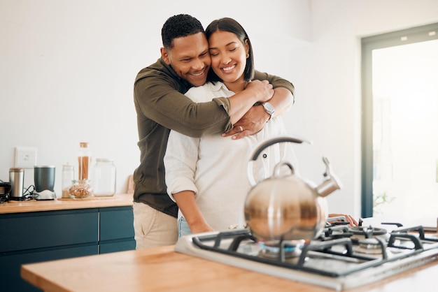 Amore romantico e legame di coppia che si abbraccia mentre si gode del tempo di qualità insieme a casa Marito amorevole che mostra affetto, cura e abbraccio alla moglie rilassante mentre prepara il tè in cucina