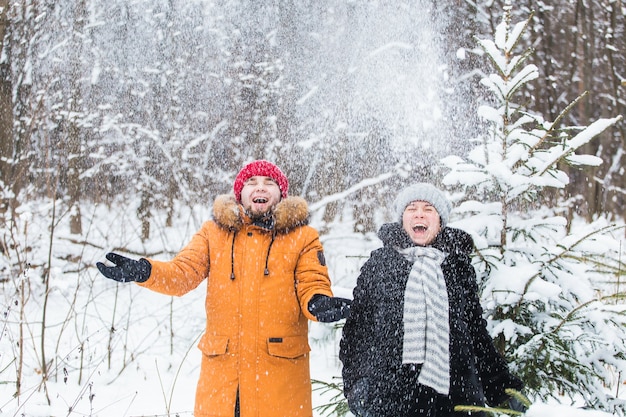 Amore, stagione, amicizia e concetto di persone - felice giovane uomo e donna che si divertono e giocano con la neve nella foresta invernale.