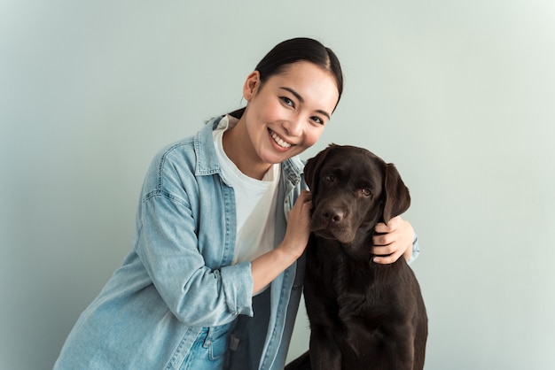 Amore tra padrone e cane. Donna amorosa che accarezza il suo animale domestico su uno sfondo grigio muro. Concept - fedele amico dell'uomo cane