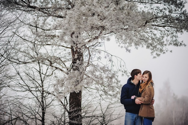 Amore uomo e donna che abbracciano all'aperto nevicate invernali.