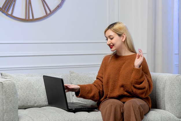 Amore virtuale carina giovane ragazza bionda in un maglione accogliente sulla data del computer a distanza sorridente