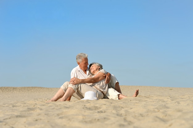 Amorevole coppia di anziani che riposa sulla sabbia in estate