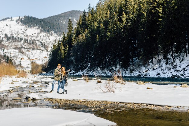 Amorevole coppia felice di viaggiatori che camminano vicino al fiume di montagna.