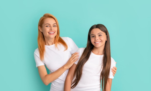 Amorevole madre allegra abbracciare la figlia in camicie bianche su sfondo blu felicità