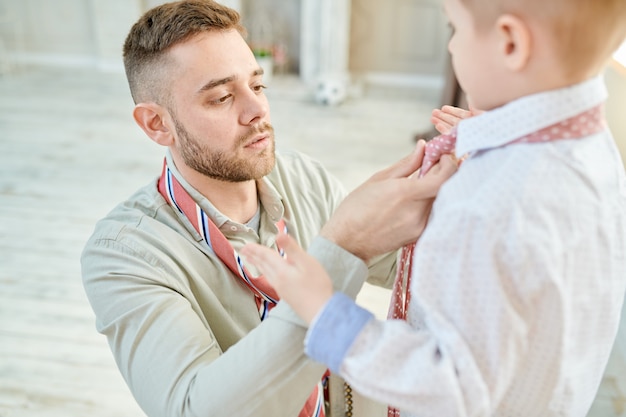 Amorevole papà annodare cravatta con figlio piccolo