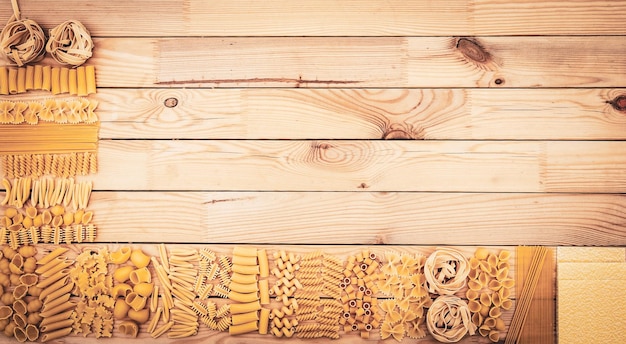 Ampia scelta di pasta cruda su un tavolo di legno concetto di cibo mediterraneo diversi tipi e forme