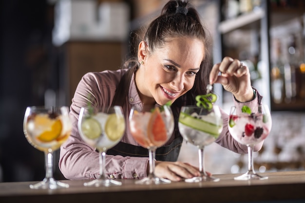 Ampia selezione di bevande gin tonic fatte in un bar da una bella cameriera.