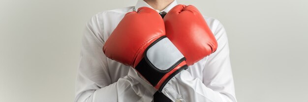 Ampia vista frontale dell'uomo d'affari che indossa guantoni da boxe rossi con le braccia incrociate sul petto.