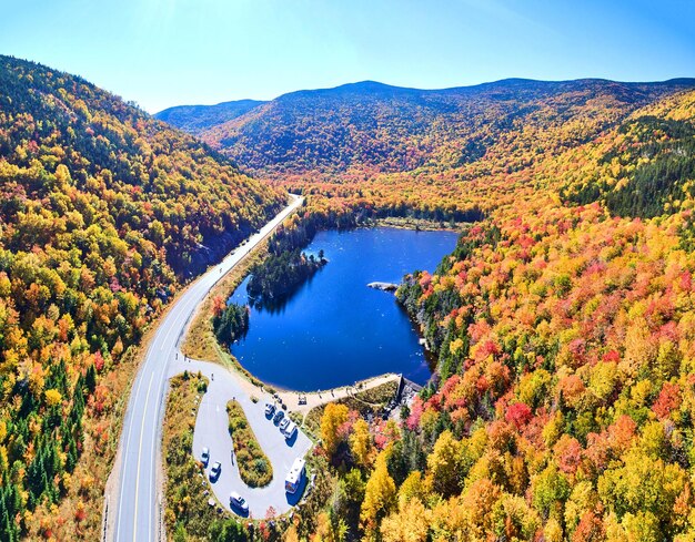 Ampio panorama aereo del lago blu e delle montagne di picco del fogliame di caduta del New Hampshire lungo la strada con t