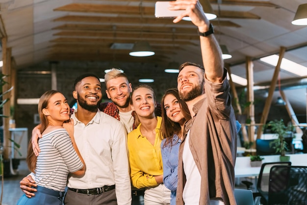 Ampio sorriso Colleghi allegri che fanno selfie in ufficio