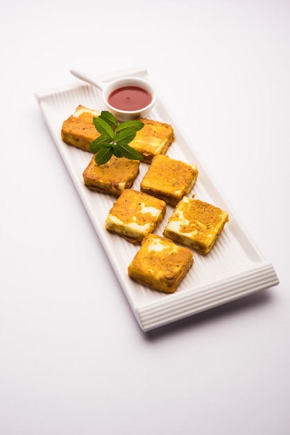 Amritsari Paneer Tikka made using cottage cheese cubes dipped in a batter made with besan, chat masala and spices and shallow fried in pan, served with ketchup