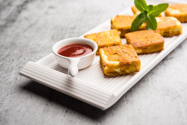 Amritsari Paneer Tikka made using cottage cheese cubes dipped in a batter made with besan, chat masala and spices and shallow fried in pan, served with ketchup