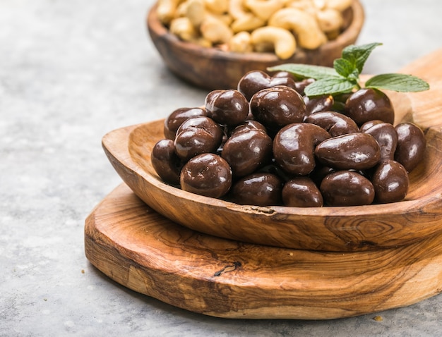 Anacardi dolci e noci ricoperte di cioccolato su superficie di pietra grigia