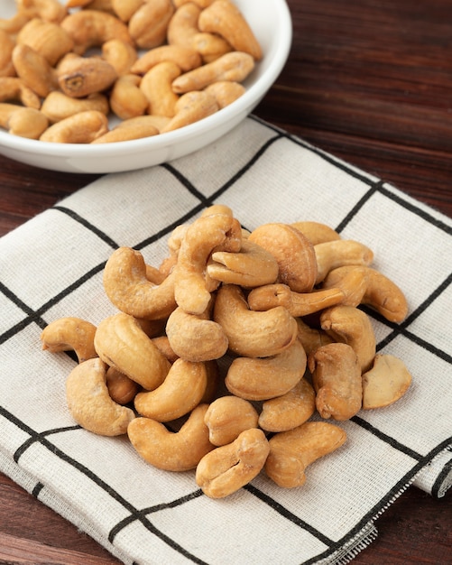 Anacardi in tovaglia sulla tavola di legno, spuntino sano, cibo vegetariano.