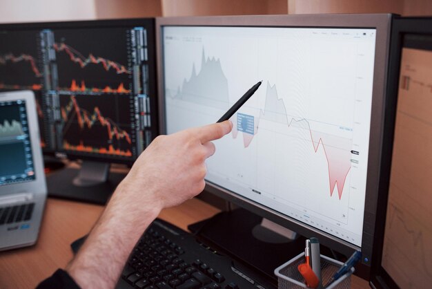 Analisi dei dati Closeup di un giovane uomo d'affari che indica i dati presentati nel grafico con la penna mentre lavora in un ufficio creativo