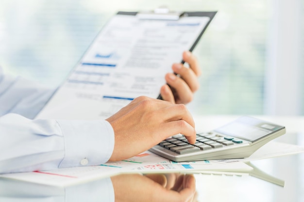 Analisi dei dati finanziari. Foto ravvicinata della mano di un uomo d'affari che conta sulla calcolatrice in ufficio.
