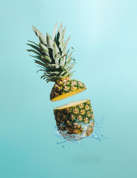 Ananas a fette con spruzzi d'acqua su sfondo blu Concetto di frutta minima Idea tropicale estiva