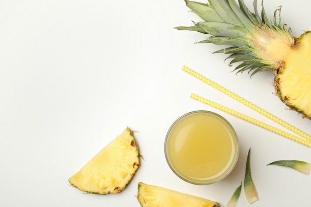 Ananas, bicchiere di succo, cannucce e fette su sfondo bianco