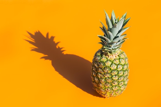 Ananas con luce dura e ombre sullo sfondo arancione alla moda