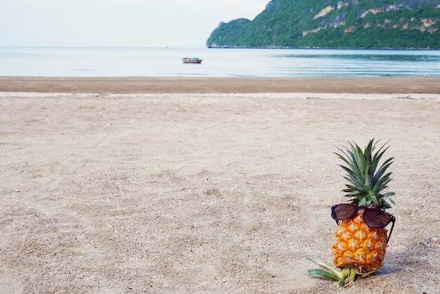 Ananas con occhiali da sole sulla sabbia. Copia spazio