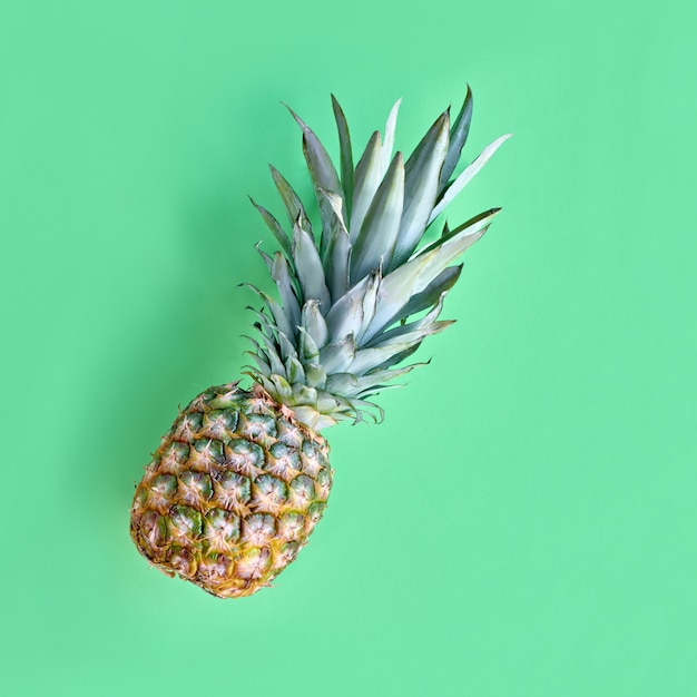 Ananas divertente in bicchieri a forma di cuore su sfondo di carta di menta neo