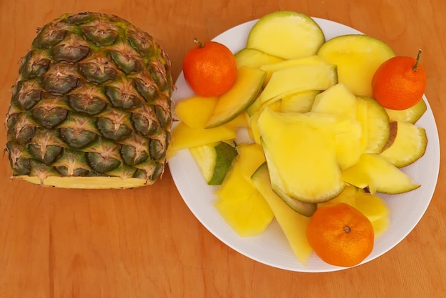 Ananas e clementine affettati in un fondo di legno del piatto