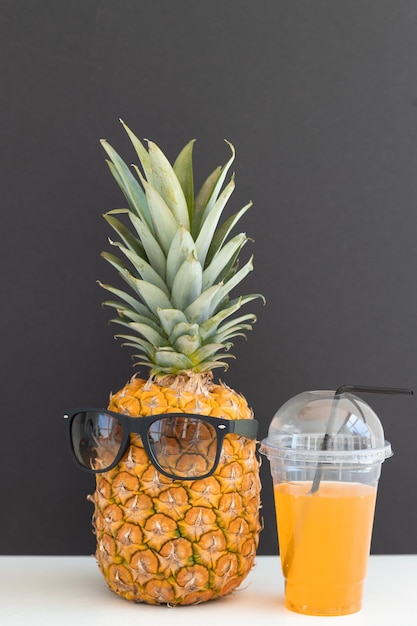 Ananas e cocco con occhiali da sole che riposano e bevono un cocktail sulla spiaggia Vacanze estive