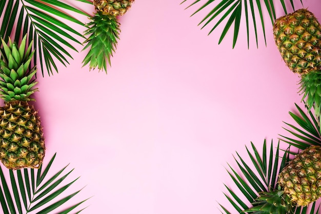 Ananas e foglie di palma tropicali su sfondo rosa pastello incisivo Concetto estivo Disposizione piatta creativa con spazio per la copia Vista dall'alto