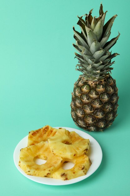 Ananas e piatto con fette grigliate su sfondo di menta.