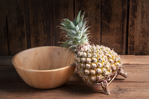 Ananas e vassoio di legno su un fondo di tavolo in legno