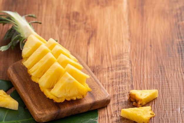 Ananas fresco tagliato su un vassoio sopra il fondo della tavola di legno scuro