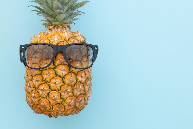 Ananas hipster con occhiali da sole su sfondo blu