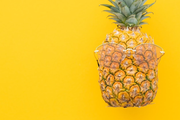 Ananas hipster con occhiali da sole su sfondo giallo