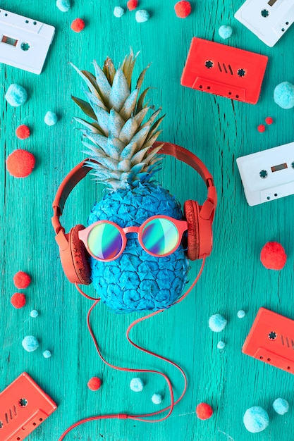 Ananas in occhiali da sole e auricolari in legno turchese con nastri audio