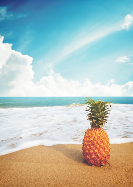 Ananas maturi sulla spiaggia tropicale sabbiosa con cielo blu chiaro. Tempo libero in estate e concetto di vacanza estiva. tono di colore dell&#39;annata.