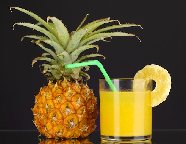 Ananas maturo e bicchiere di succo isolato sul nero