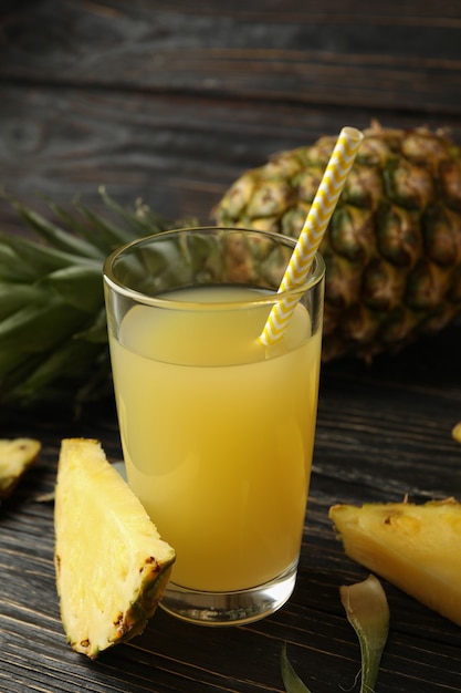 Ananas maturo e bicchiere di succo su fondo in legno