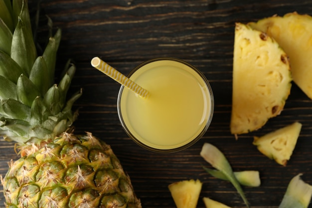 Ananas maturo e bicchiere di succo su fondo in legno