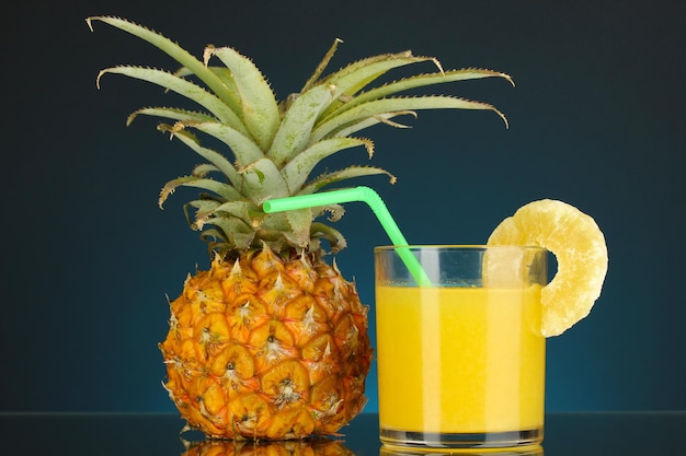 Ananas maturo e bicchiere di succo su sfondo blu scuro