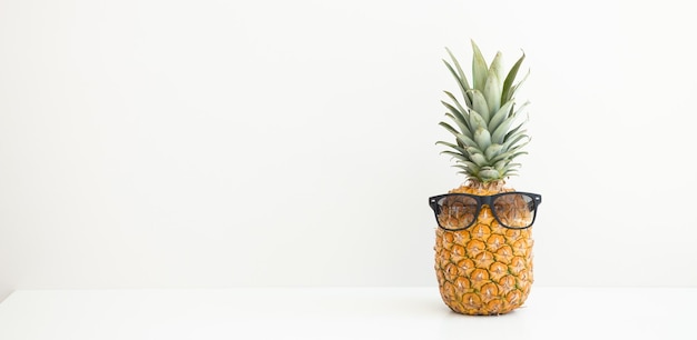 Ananas maturo in occhiali da sole su sfondo bianco Vacanze estive Ciao estate