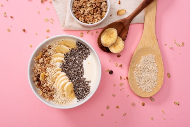 Ananas sano, ciotola di frullato di mango con cocco, banane, mirtilli e muesli. Vista dall'alto su un luminoso