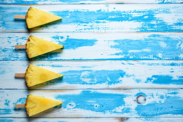 ananas su bastoncini di gelato su fondo di legno