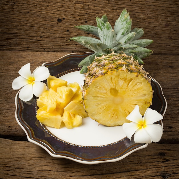 Ananas sul mezzo fiore del piatto su vecchio legno