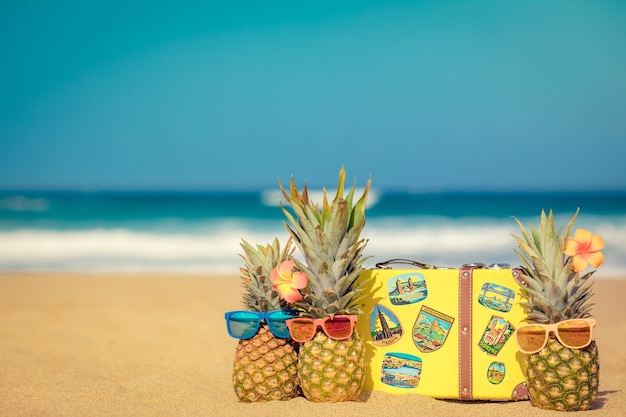 Ananas sulla spiaggia Vacanze estive e concetto di viaggio