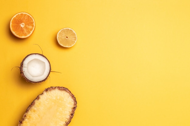 Ananas tropicale, arance, limone e cocco su uno sfondo pastello.