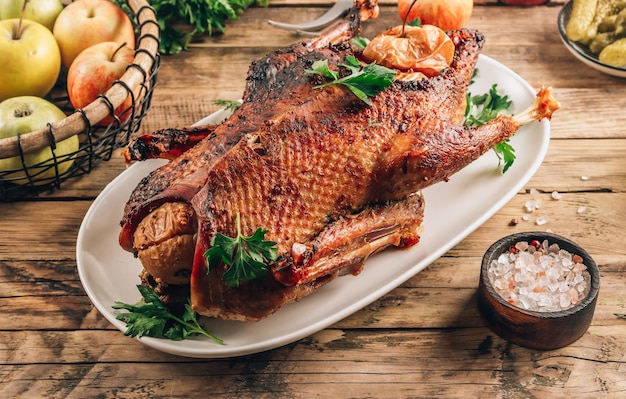 Anatra arrosto dorata intera con marinata con mele fresche per una cena festiva su sfondo rustico Foto selettiva